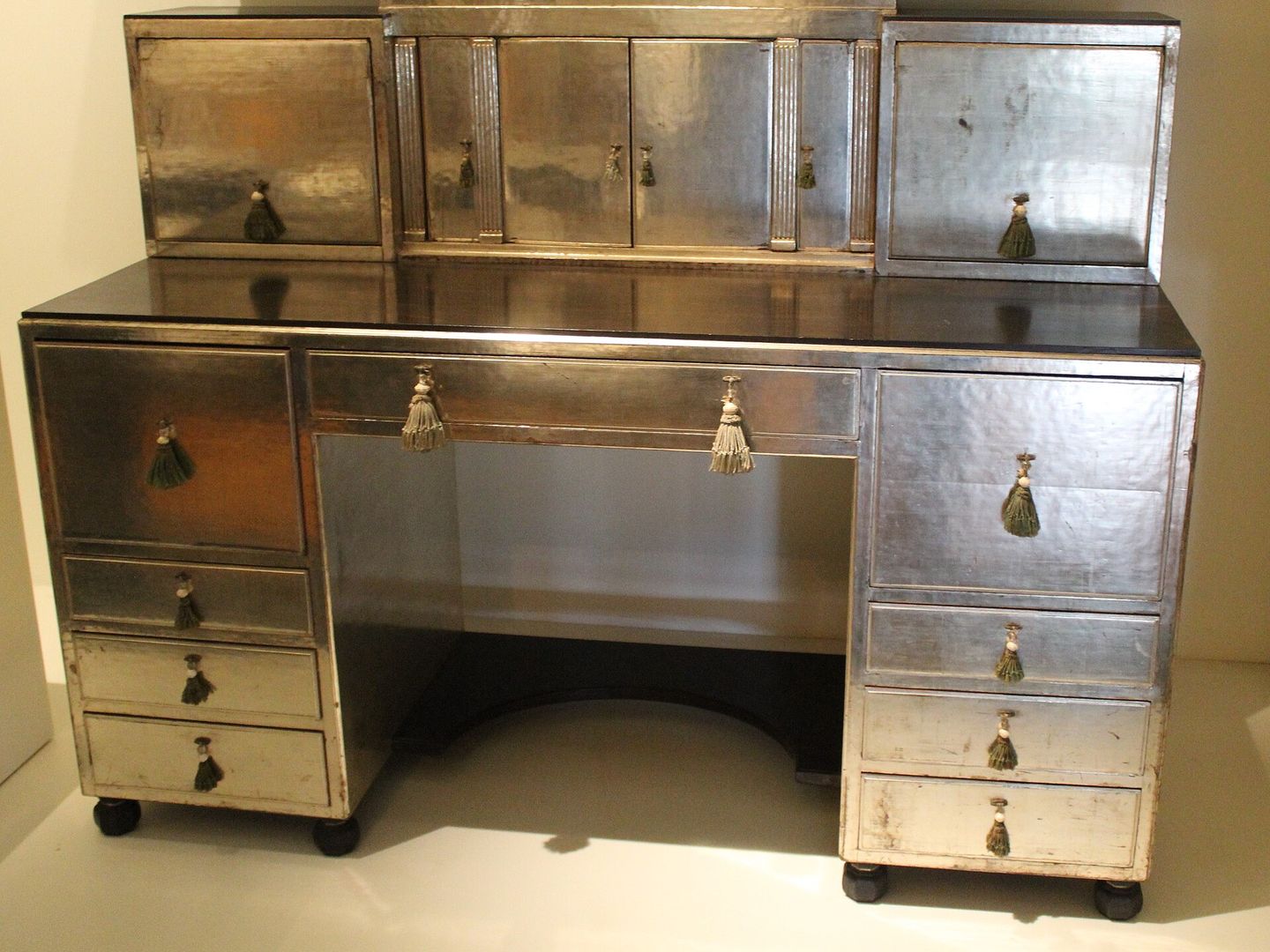 Zilverkleurig bureau met rechte lijnen, acht laden en een opbouw met kastjes