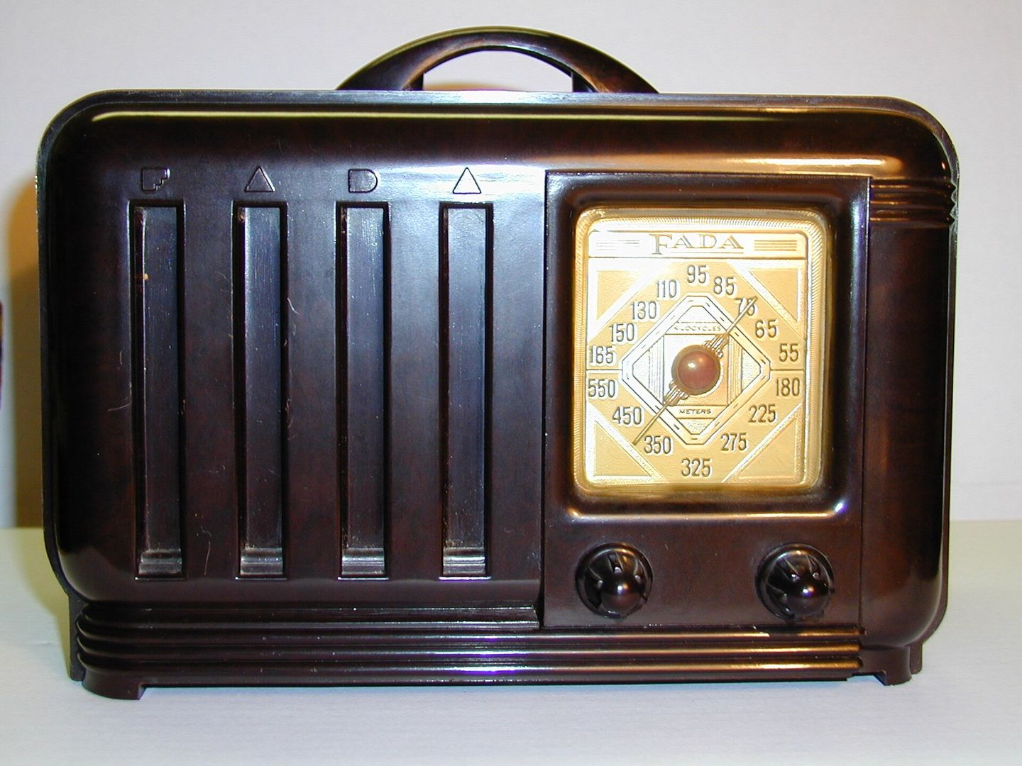Bruine radio van bakeliet met verticale ribben, een handvat en een vierkante afstemschaal