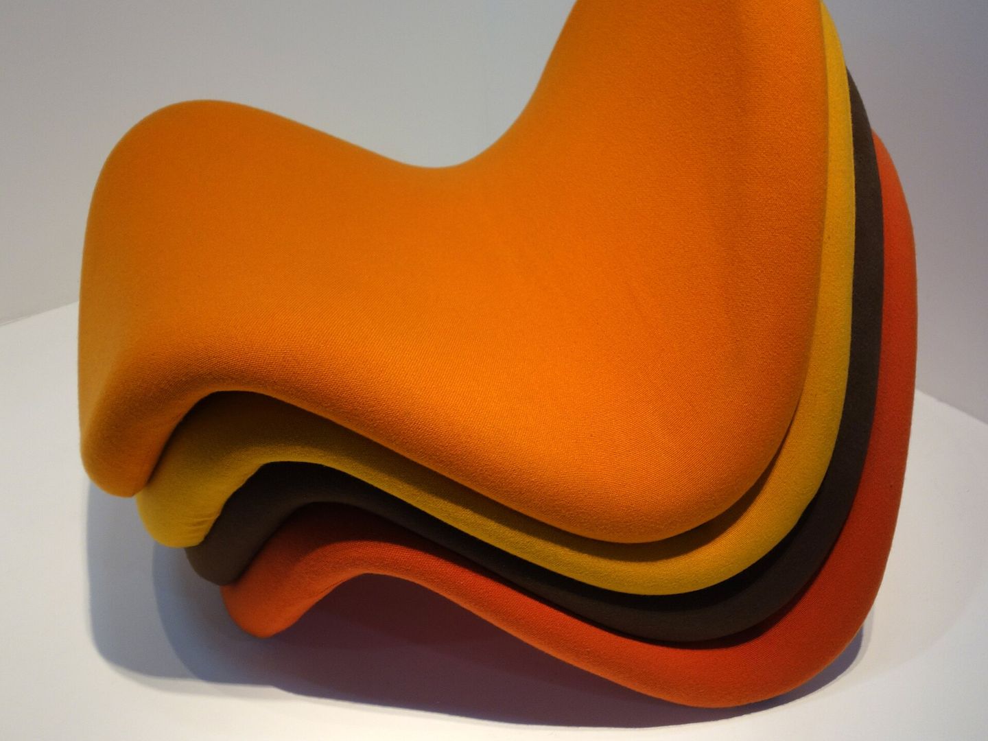 Vier gestapelde Tongue-stoelen in oranje, geel, bruin en rood