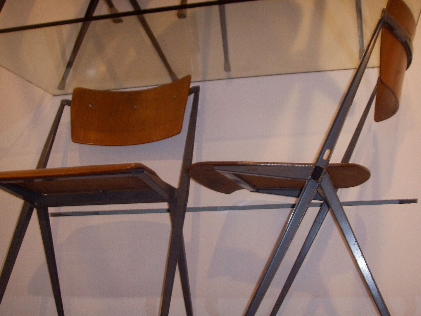 Twee stoelen met houten zitting en rug op gekruiste grijze stalen poten, van Wim Rietveld voor Ahrend-De Cirkel