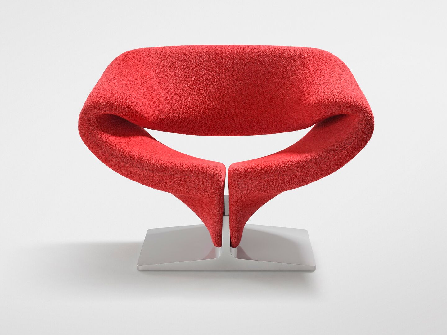 Een rode fauteuil in de vorm van een gekrulde band op een witte voet