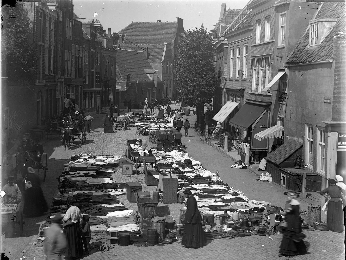 Straat vol uitgestalde kleding en spullen op een vlooienmarkt in Leiden, in zwart-wit
