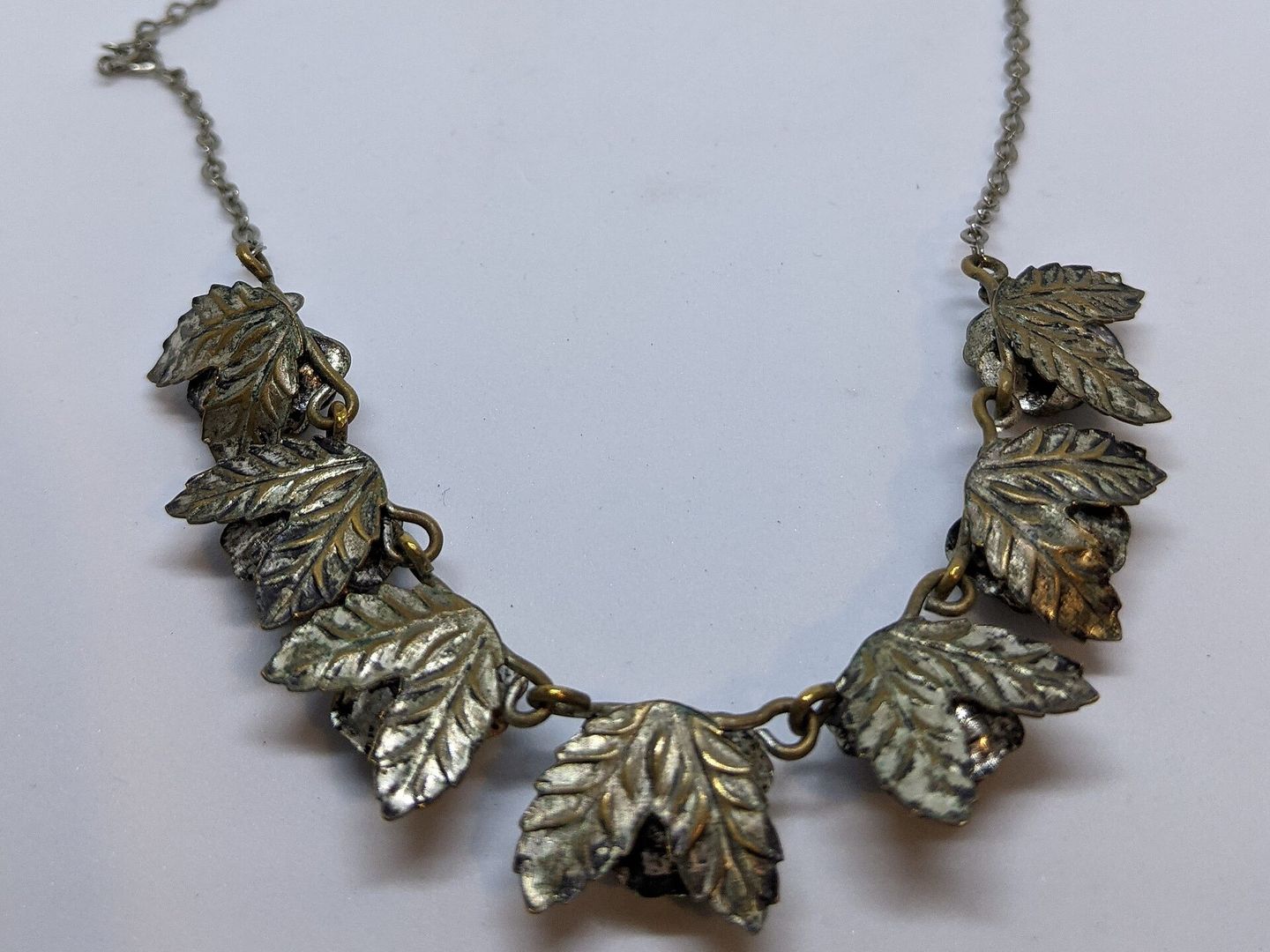 Achterkant van een metalen ketting met bladvormige schakels en zichtbare verbindingsringetjes