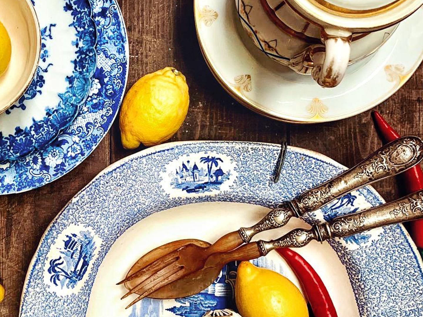 Blauw-witte borden, een kop en schotel, zilveren slabestek en citroenen op een houten tafel