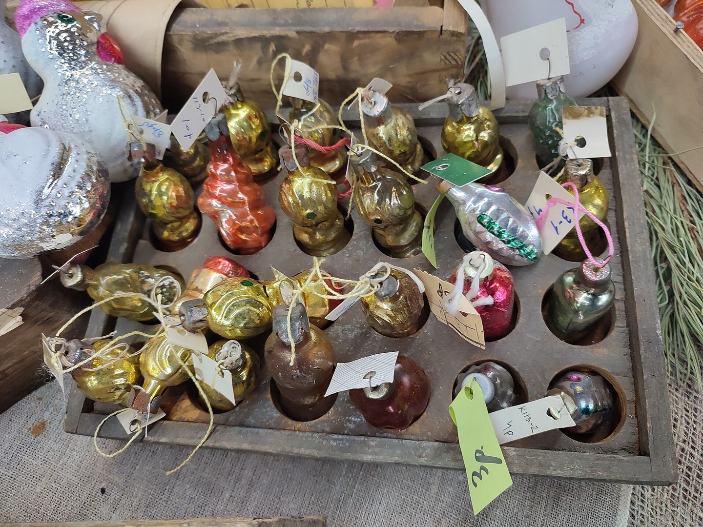 Glazen kerstballen en figuren met metalen kapje en prijskaartje in een sorteerbak