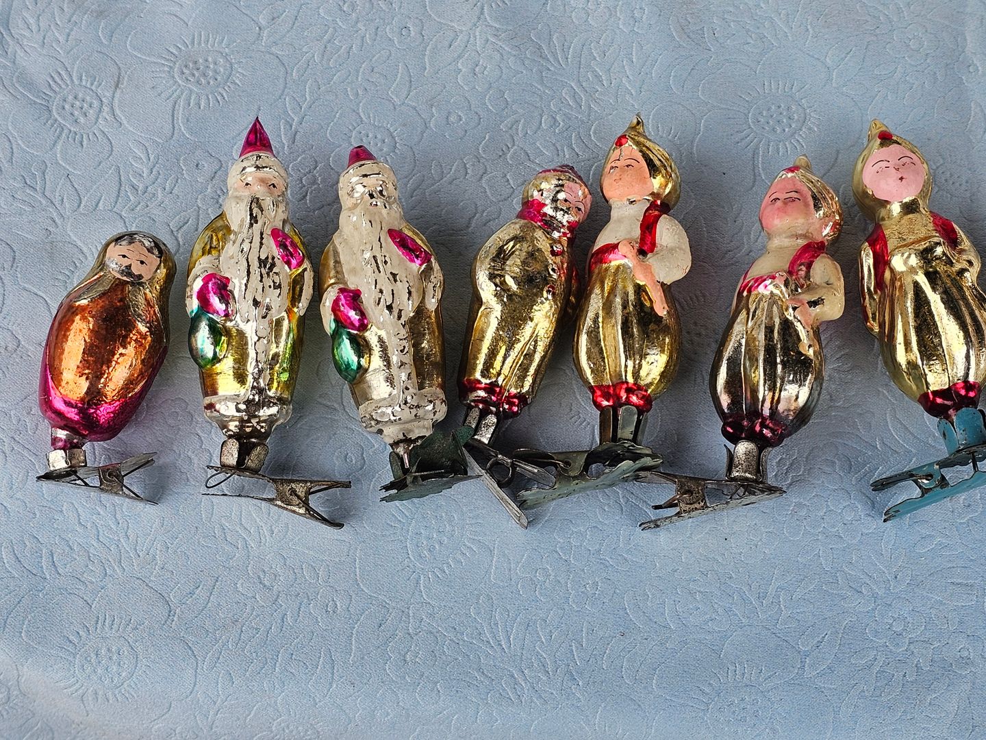 Glazen kerstmannen en poppetjes met een klemmetje op een tafel van een vlooienmarkt