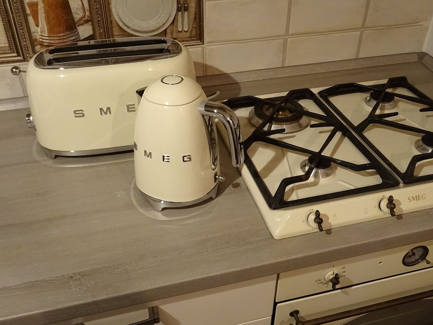 Een crèmekleurige waterkoker, broodrooster en gaskookplaat met afgeronde vormen op een aanrecht