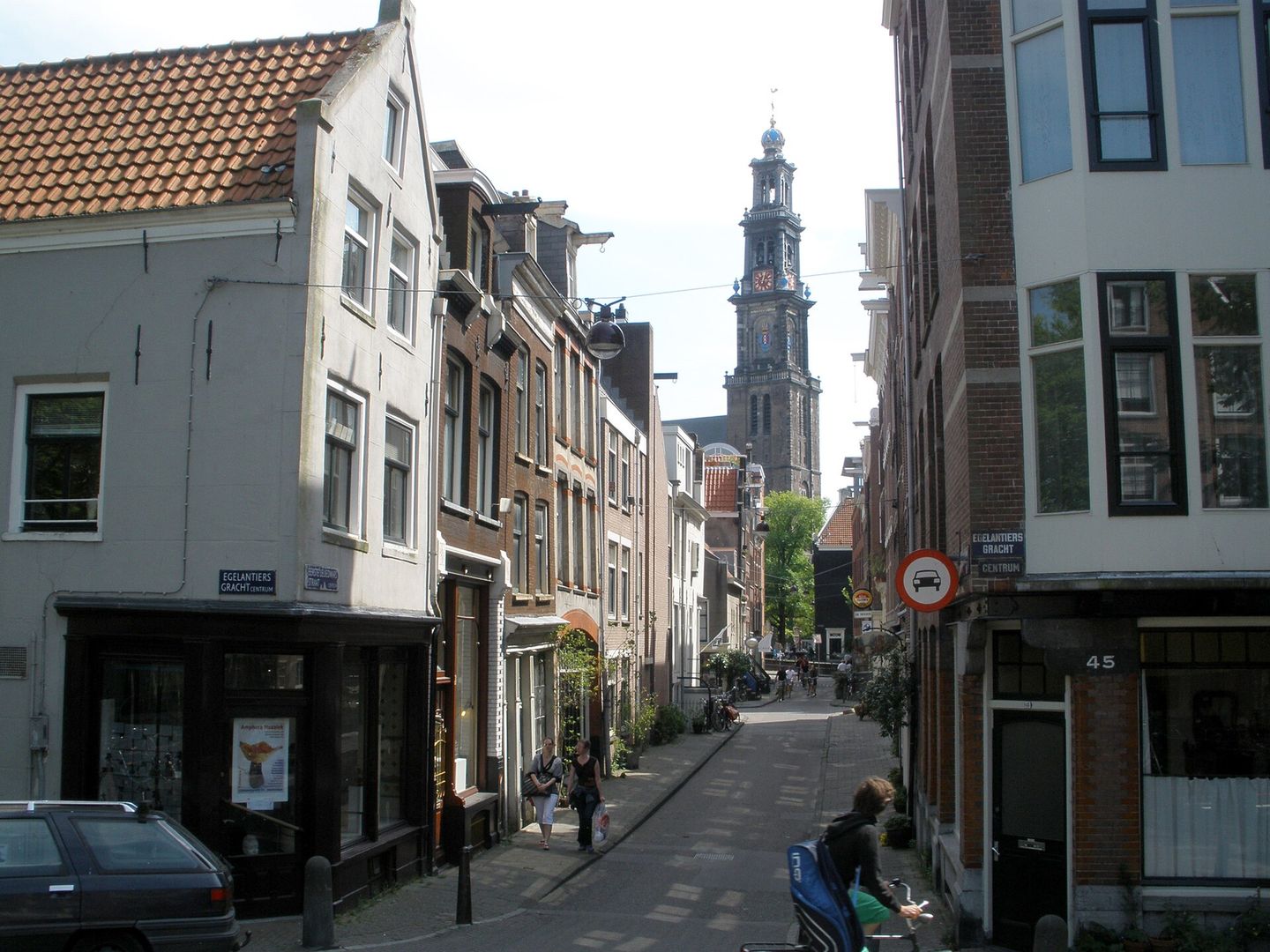 Smalle straat in de Jordaan met oude gevels en de Westertoren op de achtergrond