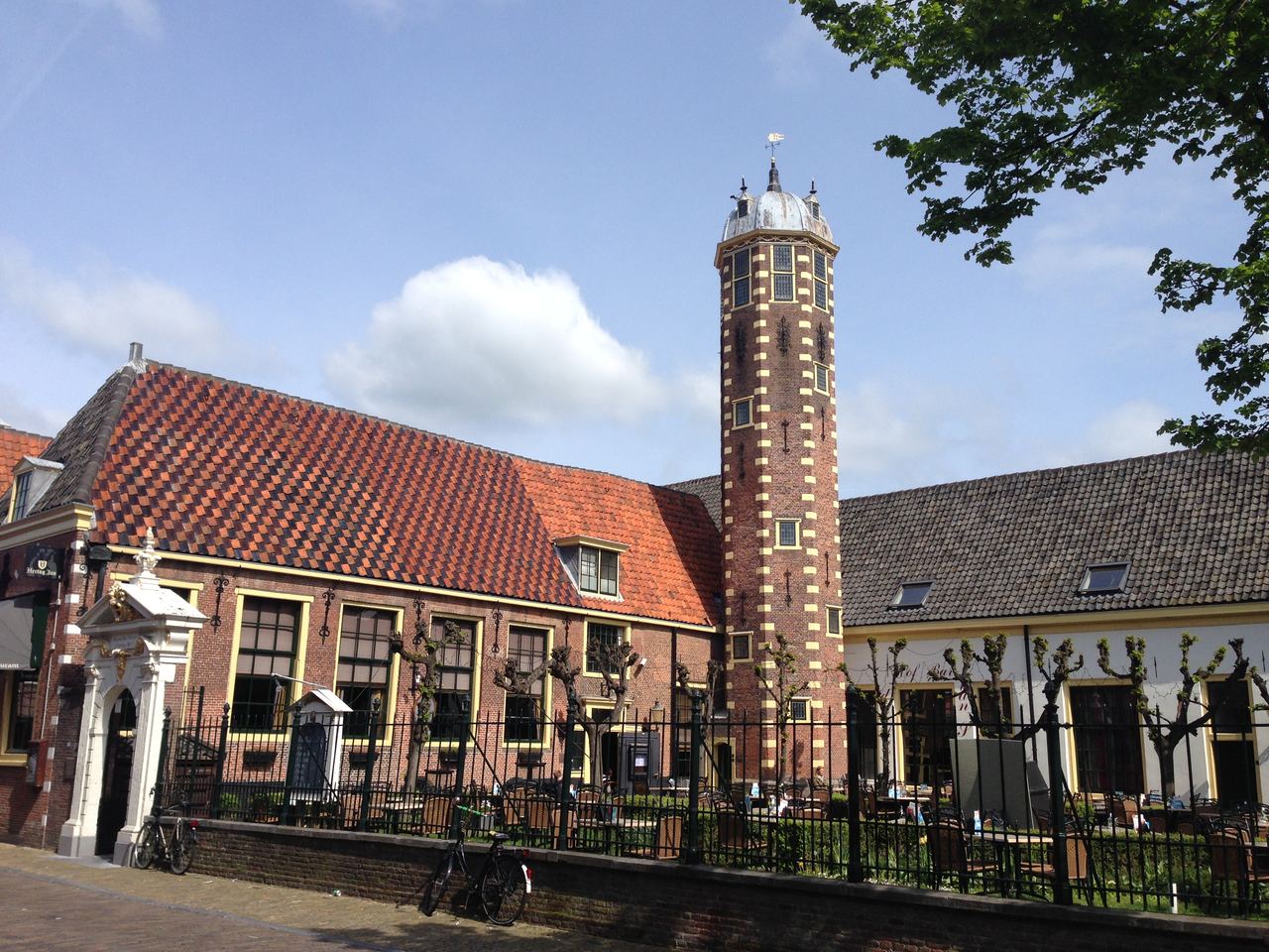 Hof van Sonoy met rode pannendaken, achthoekige toren en wit poortje achter een smeedijzeren hek