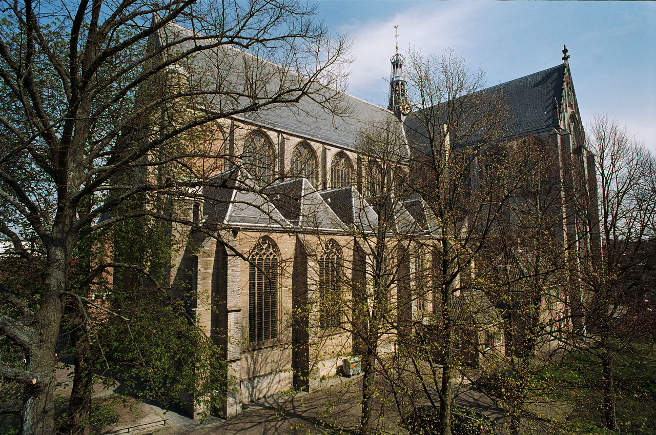 Zuidwestzijde van de gotische Grote of Sint-Laurenskerk met spitsboogramen en dakruiter, deels achter kale bomen