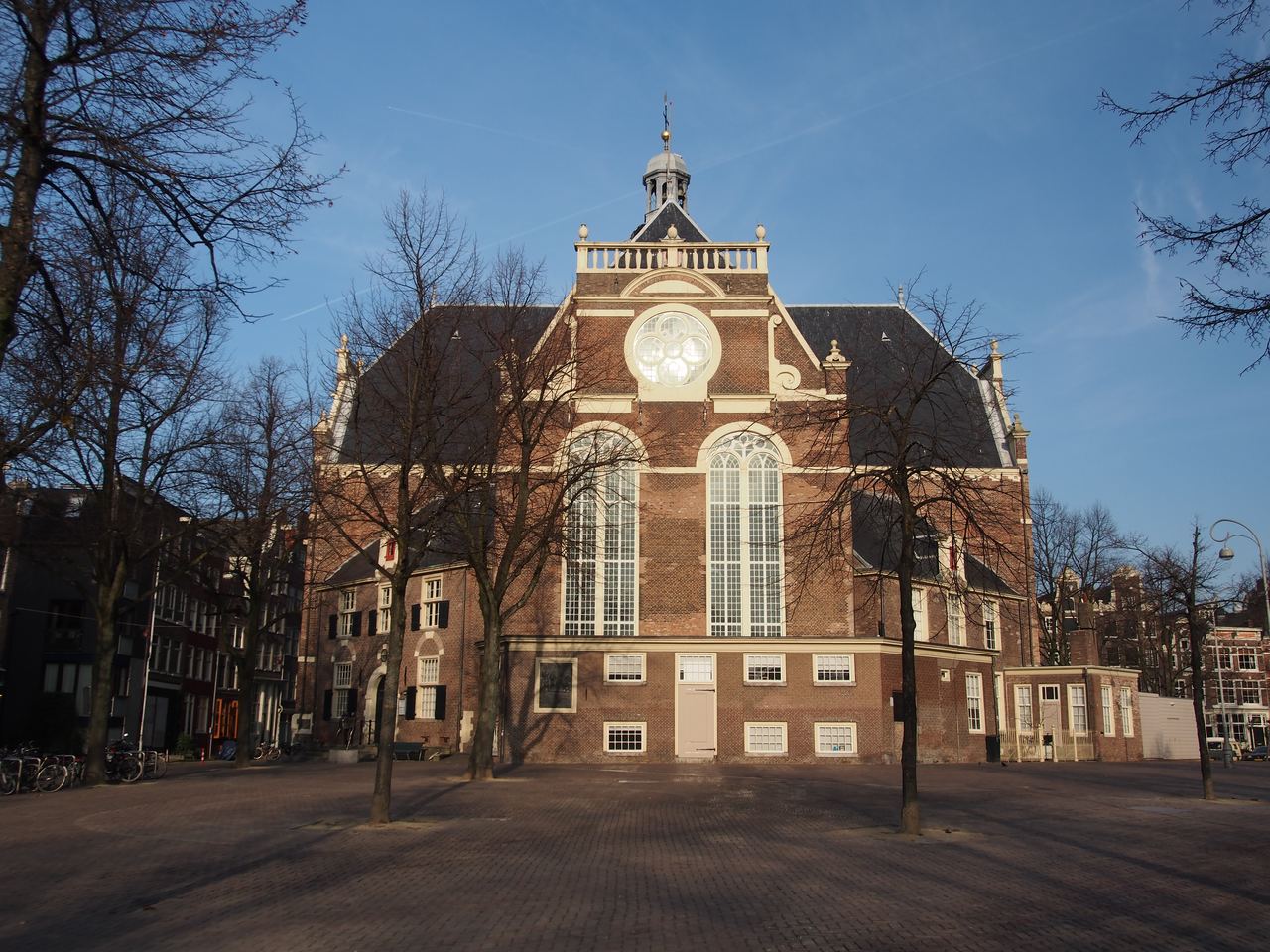 De bakstenen Noorderkerk aan een plein met kale bomen