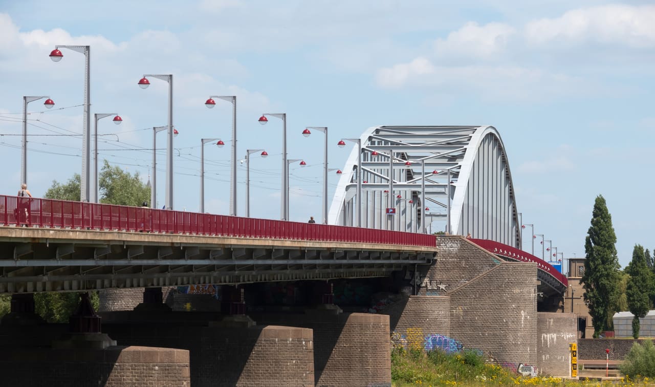 De John Frostbrug met haar stalen boog en rode leuningen over de Nederrijn