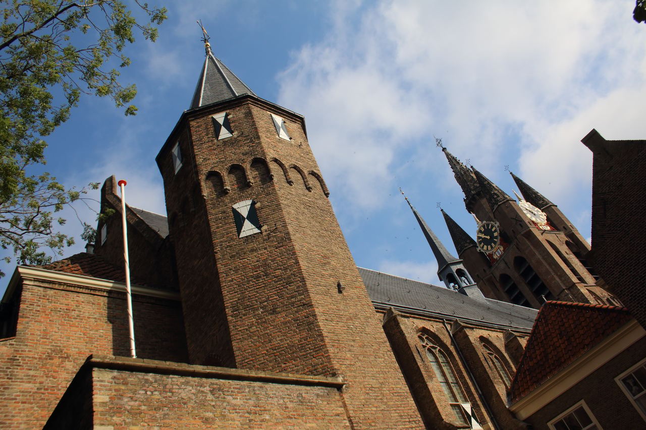 Bakstenen toren van het Prinsenhof met daarachter de torenspitsen van de Oude Kerk