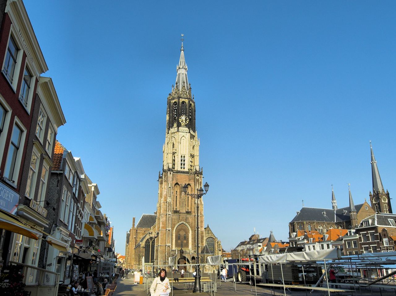 De Markt met de hoge toren van de Nieuwe Kerk en gevels aan weerszijden onder een blauwe lucht