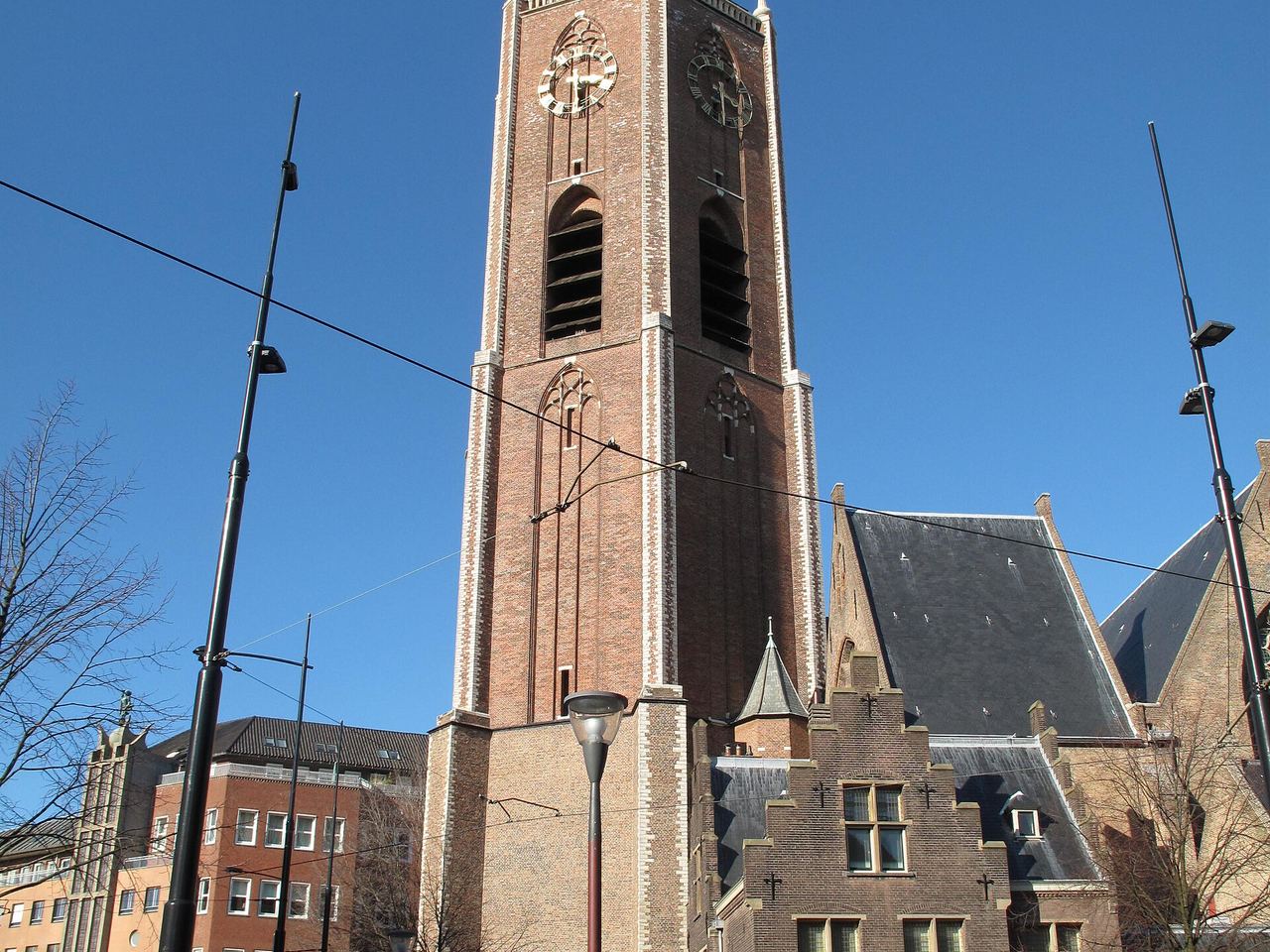 De bakstenen Grote Kerk met de hoge toren tegen een blauwe lucht