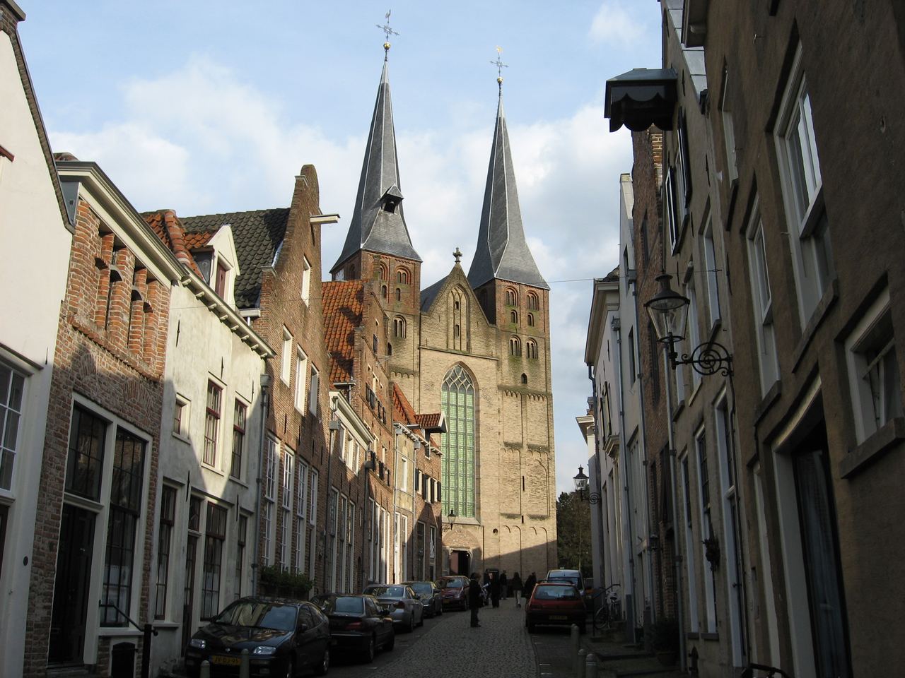 De Bergkerk met twee spitse torens aan het eind van de smalle Bergstraat met historische gevels