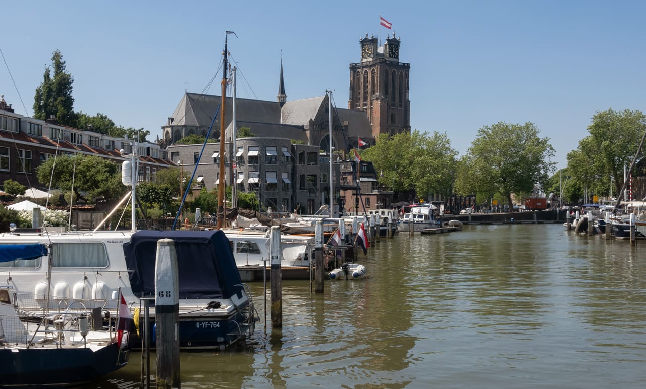 De Grote Kerk met haar onvoltooide toren boven de huizen en de jachten in de haven