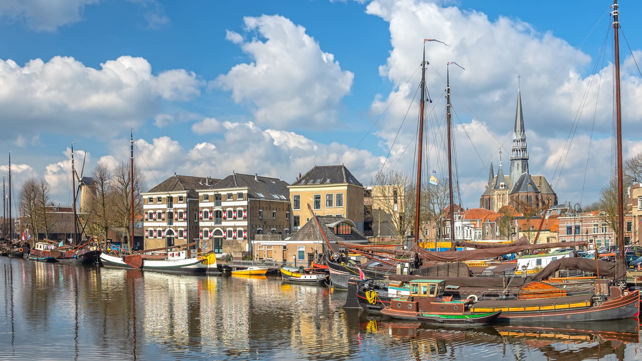 Historische zeil- en vrachtschepen in de Museumhaven, met pakhuizen en een kerktoren op de achtergrond