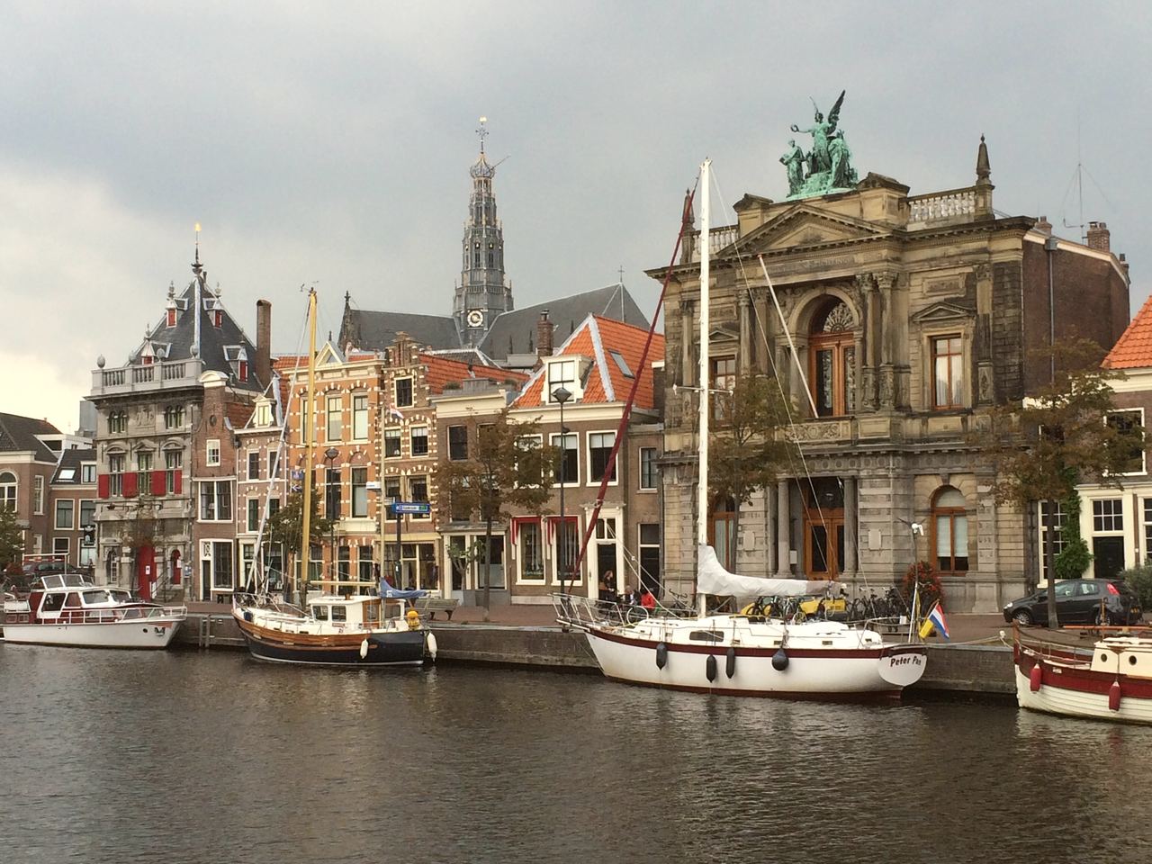 Het Spaarne met zeilboten, links de Waag, in het midden de toren van de Sint-Bavokerk en rechts Teylers Museum
