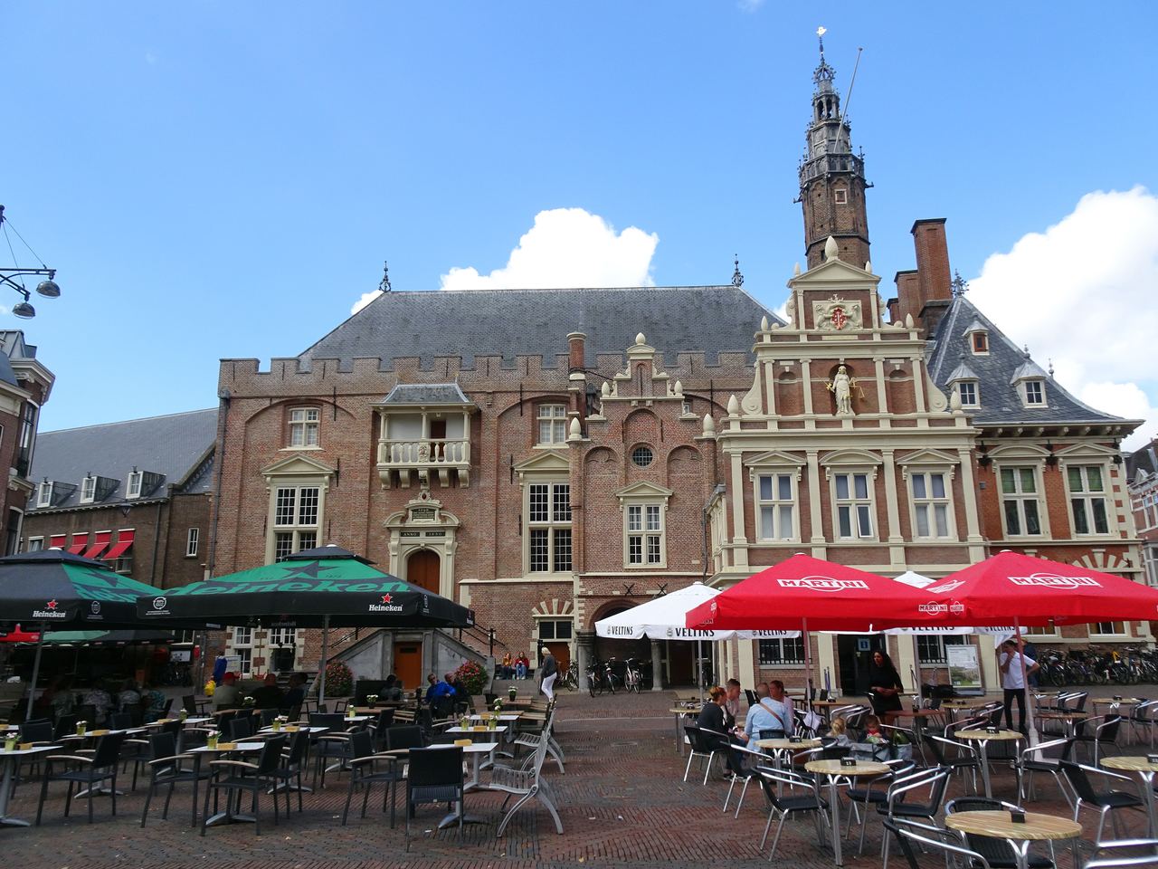 Het stadhuis met toren en trapgevels aan de Grote Markt, met terrassen en parasols ervoor