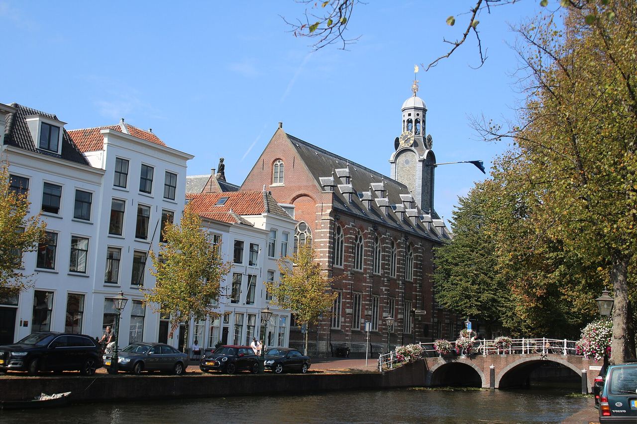 Het Rapenburg met witte grachtenpanden, het bakstenen Academiegebouw met torentje en de stenen Nonnenbrug over het water