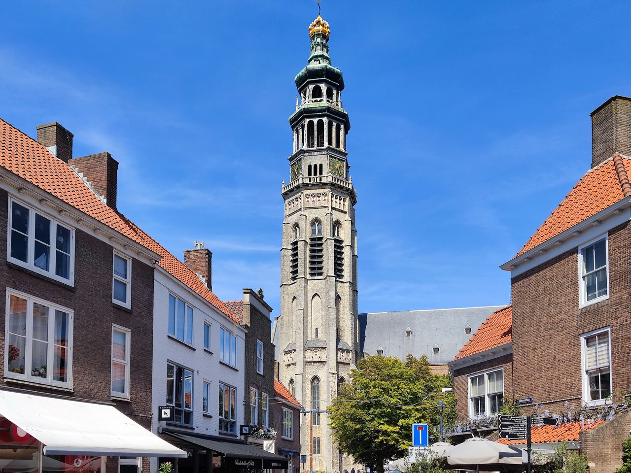 De Lange Jan met gouden kroon boven de Nieuwe Kerk, gezien door een straat met oude gevels