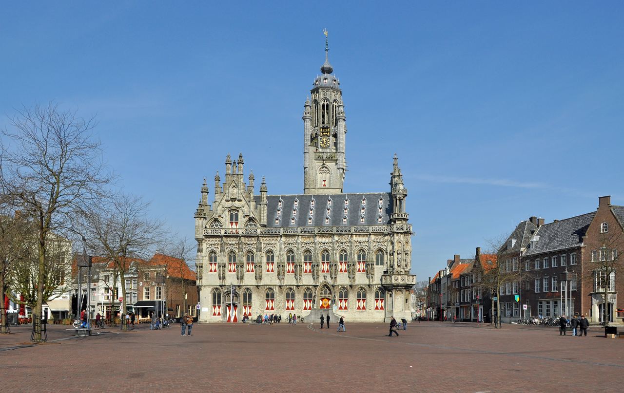 Het laatgotische stadhuis met slanke toren op de brede Markt van Middelburg onder een blauwe lucht