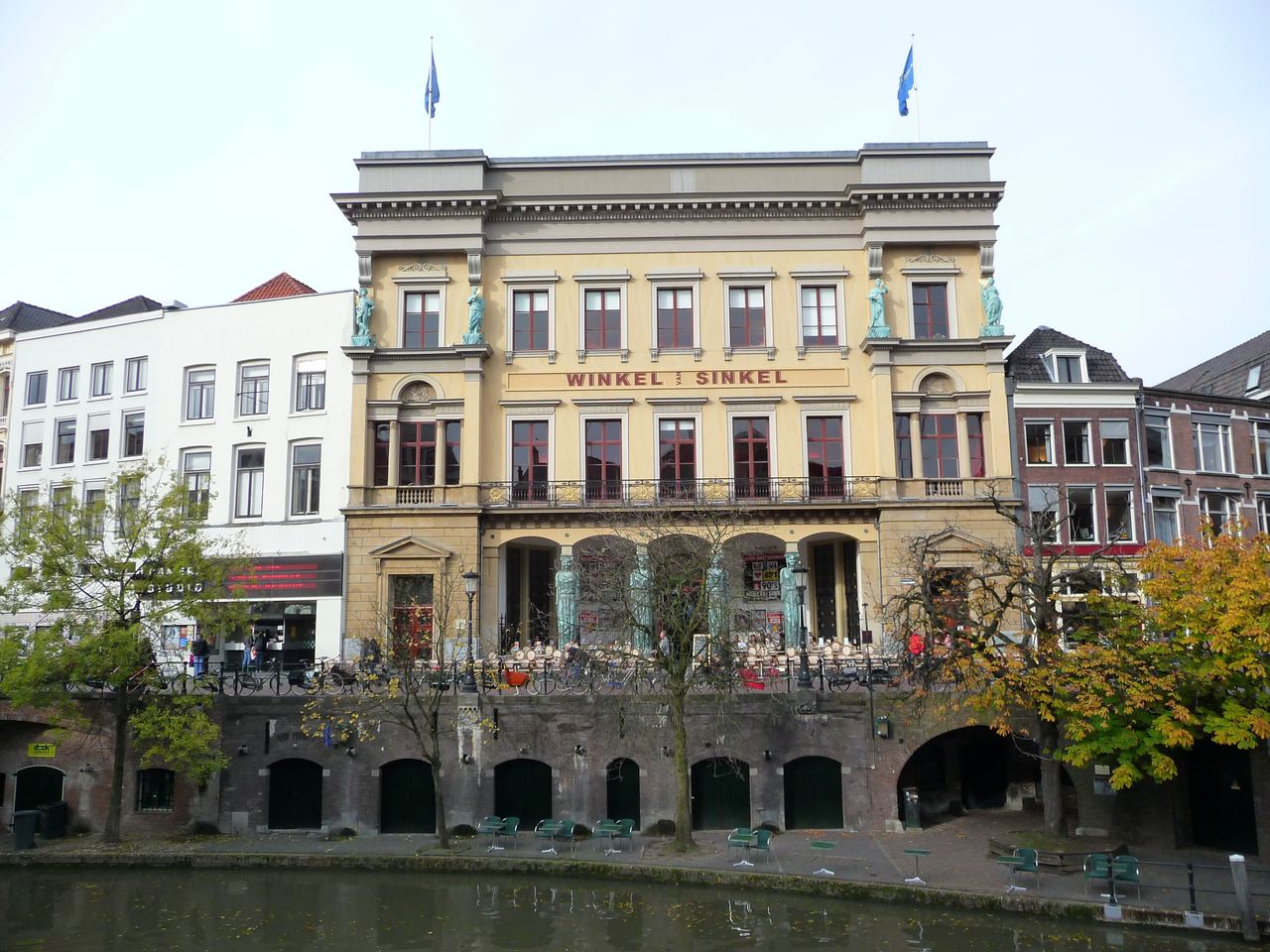 Gele neoclassicistische gevel van de Winkel van Sinkel met beelden als zuilen, boven de werfkelders aan de Oudegracht