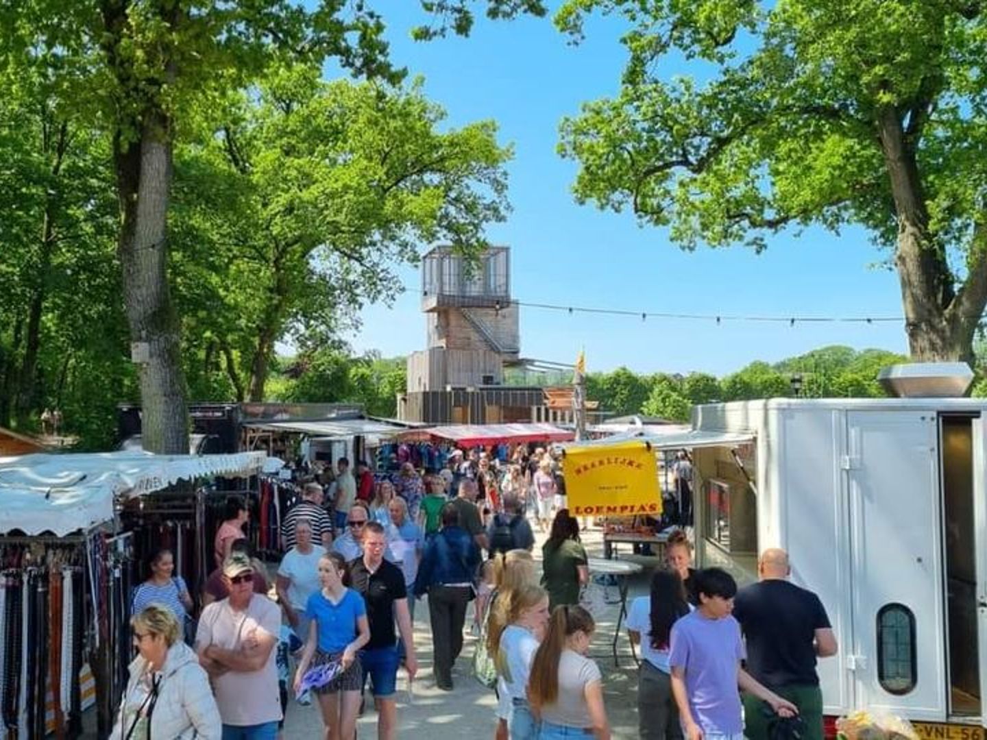 Kramen en publiek tussen de hoge bomen tijdens een eerdere Boerestreekmarkt