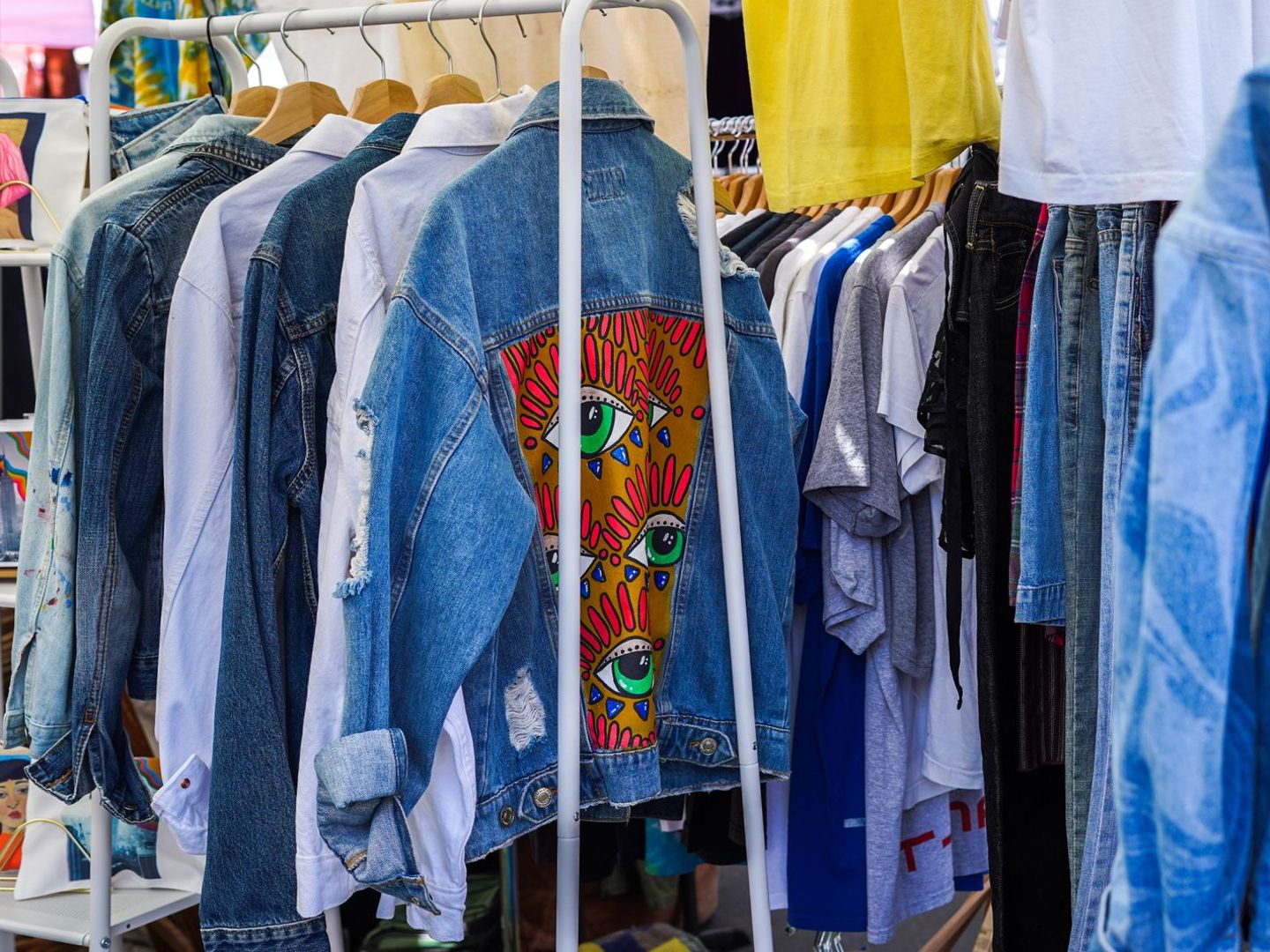 Rek met spijkerjasjes en overhemden op een vlooienmarkt