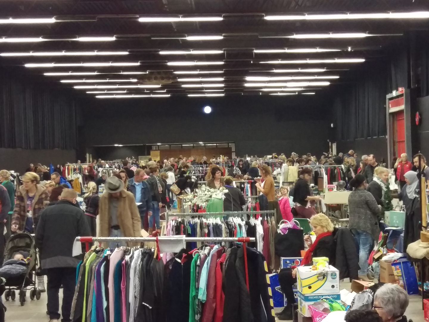 Bezoekers tussen kledingrekken en kramen op de Stadjersmarkt in de hal van MartiniPlaza