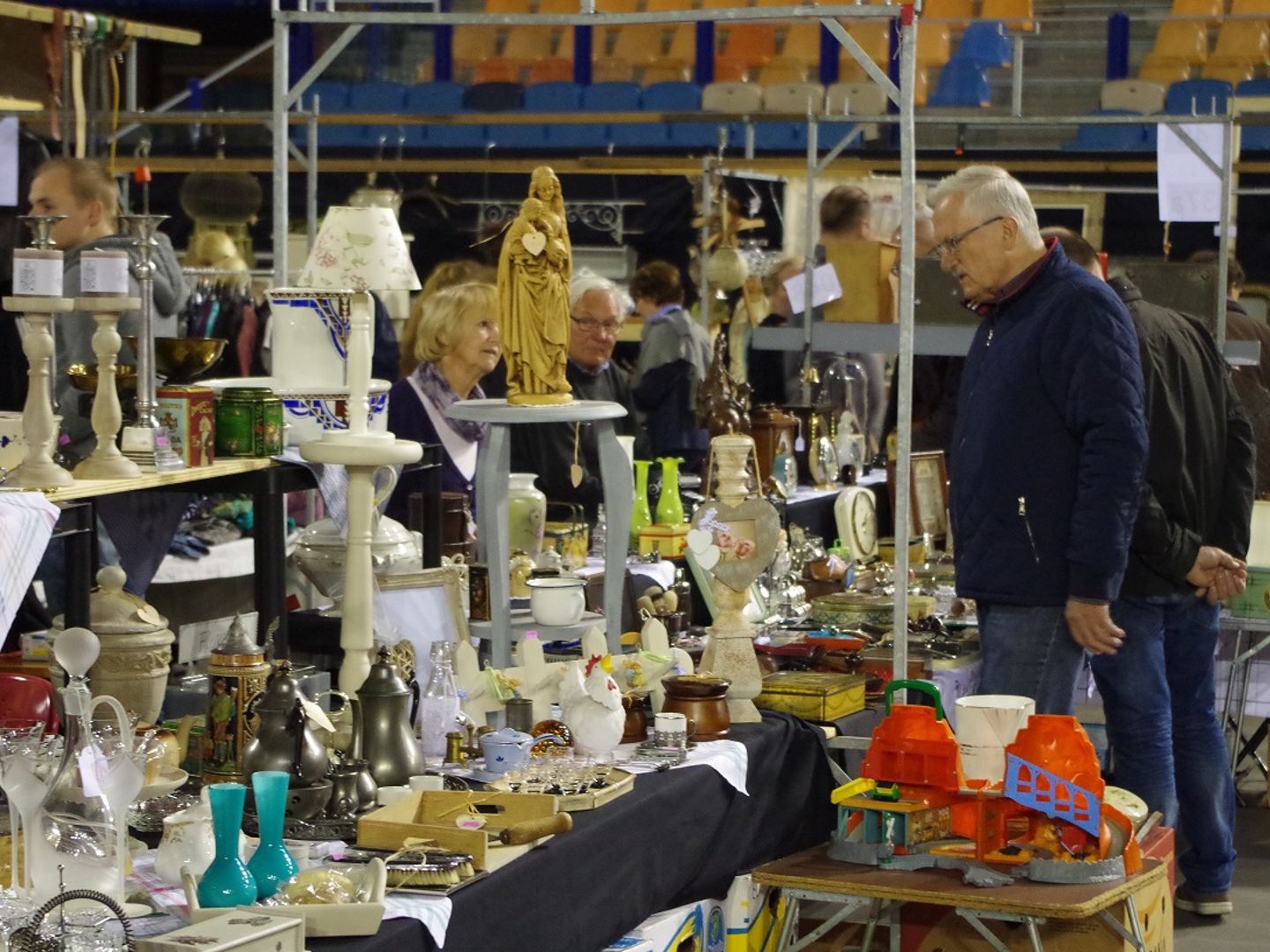 Kramen met brocante en curiosa op de vloer van het GelreDome, met de blauwe en oranje tribunes erachter