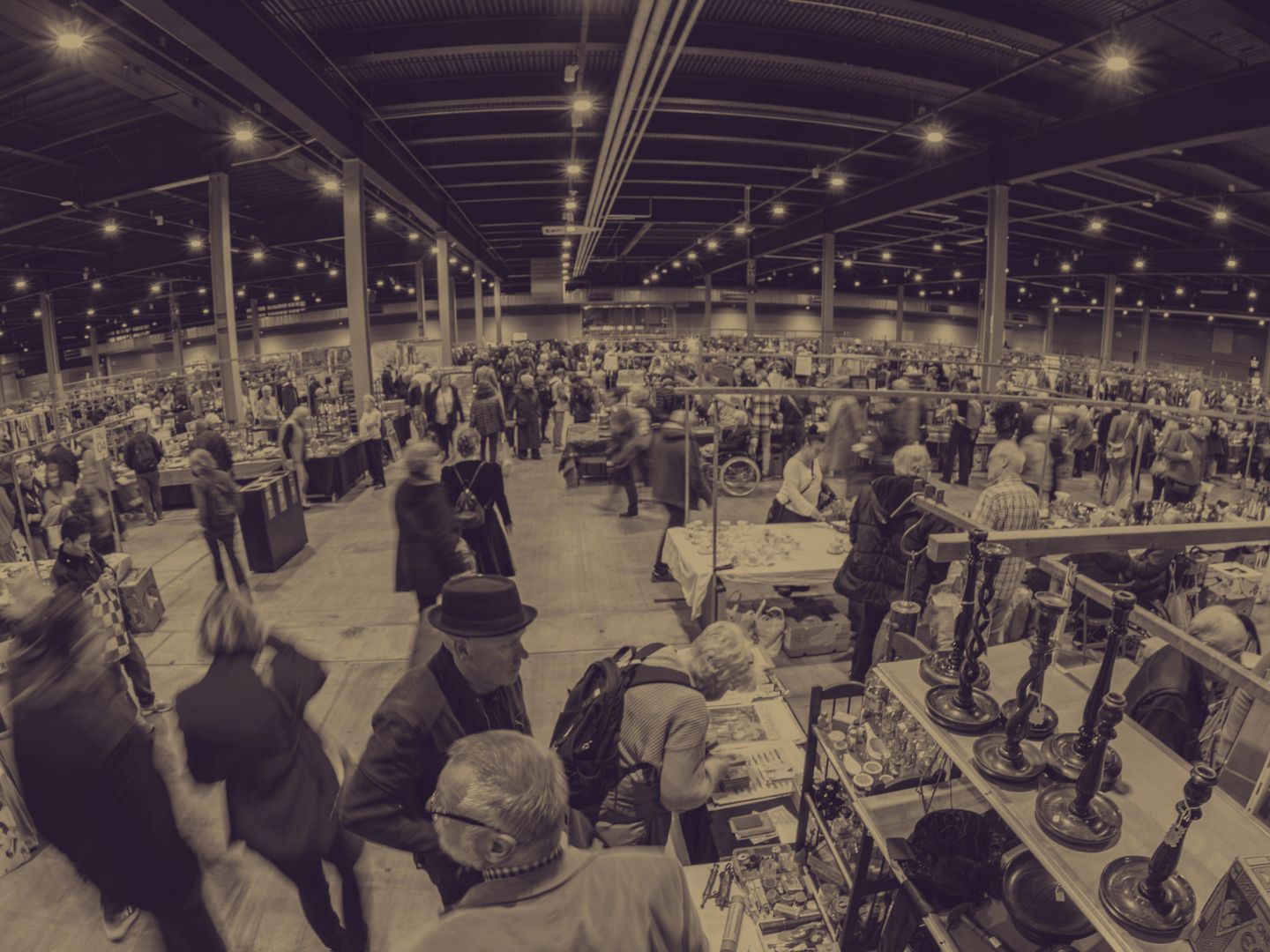 Drukke beurshal van de VerzamelJaarbeurs met rijen kramen en bezoekers, in sepiatinten