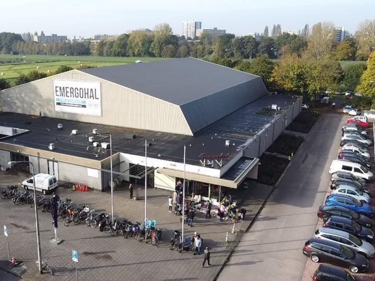 Luchtfoto van de Emergohal met de parkeerplaats ervoor