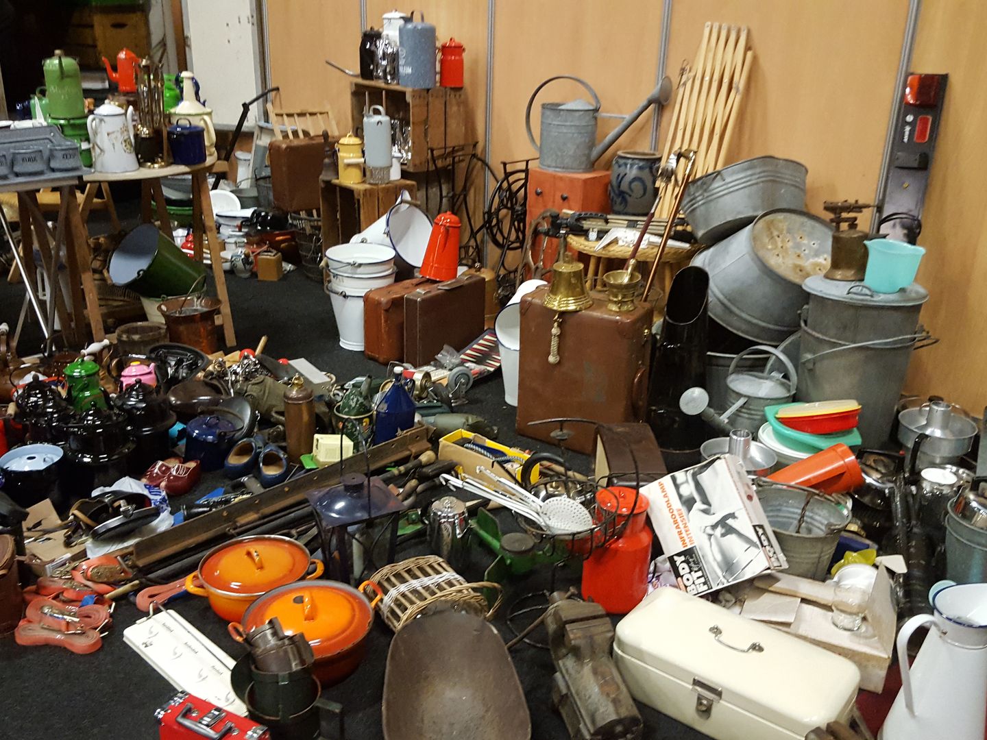 Emaille kannen, koperen pannen en oude gereedschappen op een kraam van de vlooienmarkt in Hardenberg