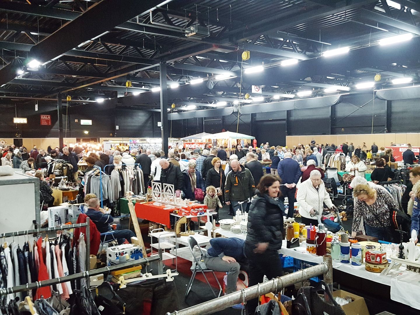 Drukte tussen de kramen en kledingrekken op de vlooienmarkt in de Evenementenhal Hardenberg