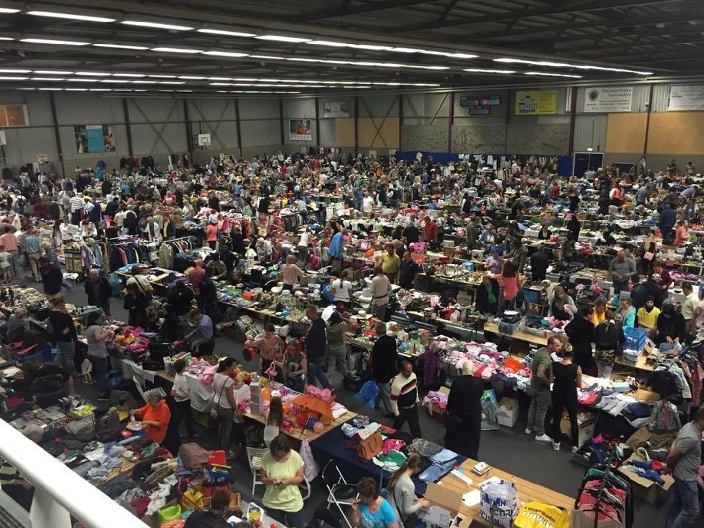 Drukte tussen de kramen met tweedehands spullen in Sporthal De Schilp tijdens een eerdere vlooienmarkt