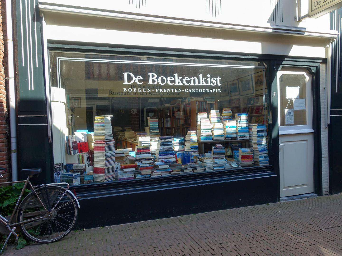 Etalage van De Boekenkist met stapels boeken achter het raam en de naam van de winkel op het glas