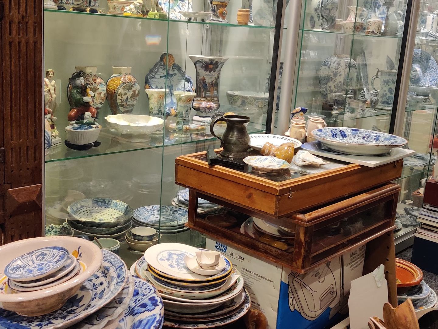 Interieur van Art & Antiques Léon-Paul van Geenen met vitrines vol blauw-wit aardewerk en borden