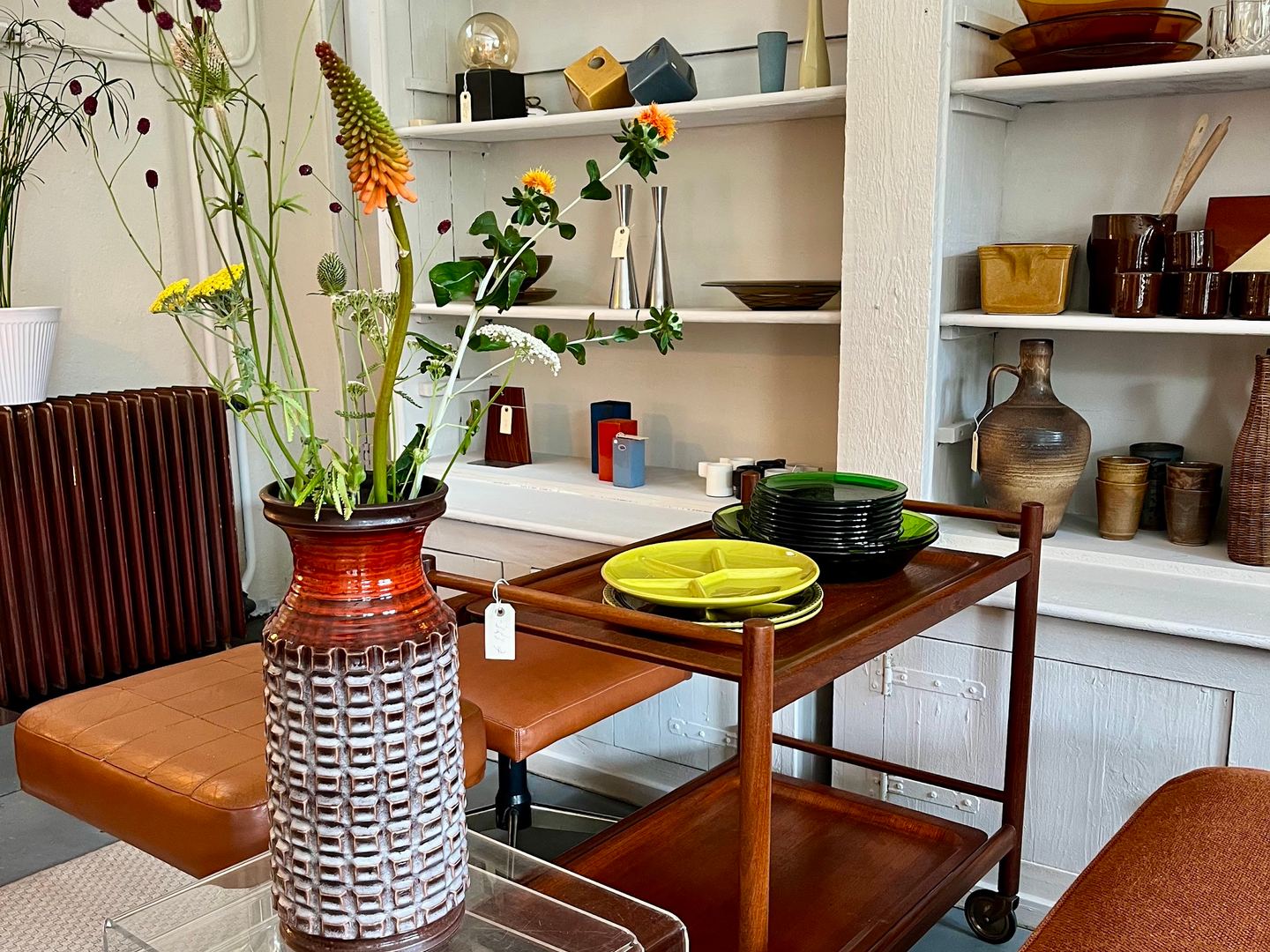 Interieur van Atelier Vintage & Design met vintage keramiek op wandplanken en een teakhouten serveerwagen