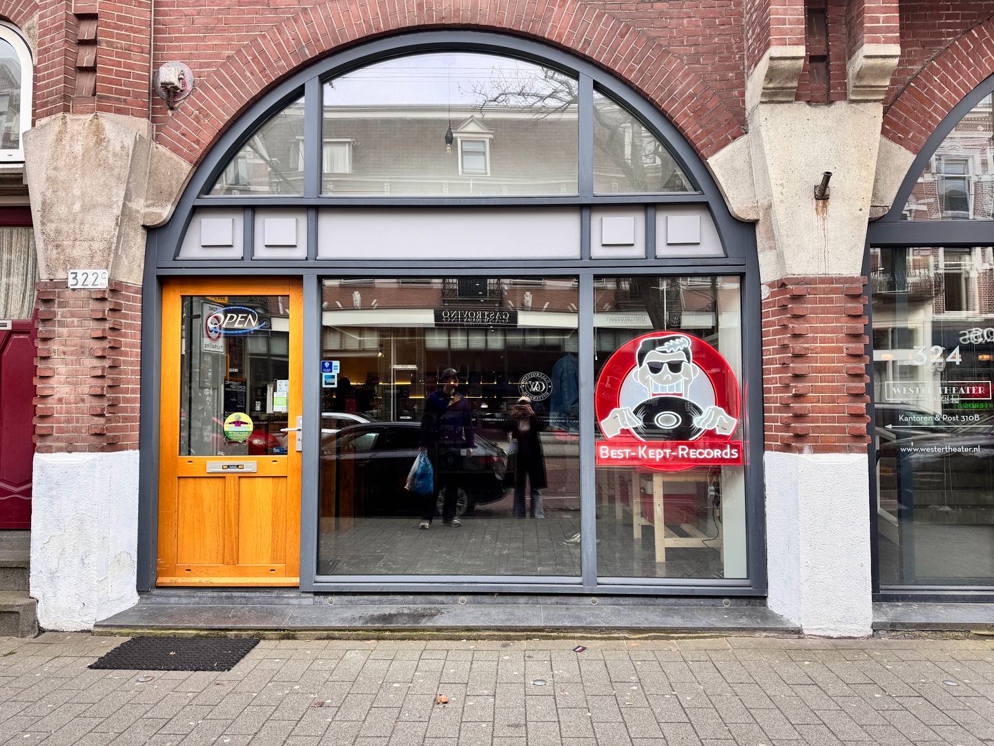 Gevel van Best Kept Records met boogvormige pui, houten deur en het logo op het raam