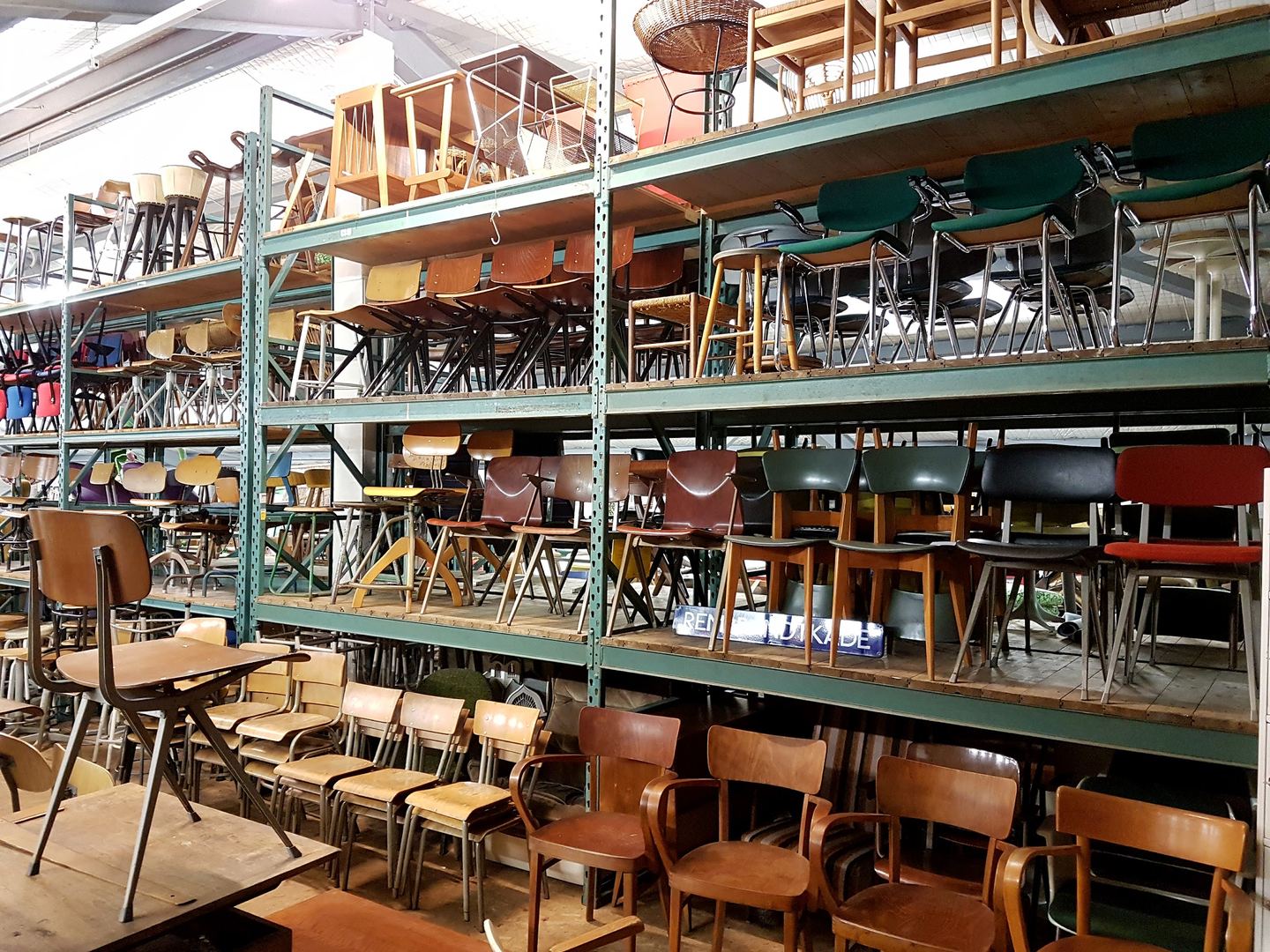 Stellingen vol vintage stoelen in de loods van Bestwelhip
