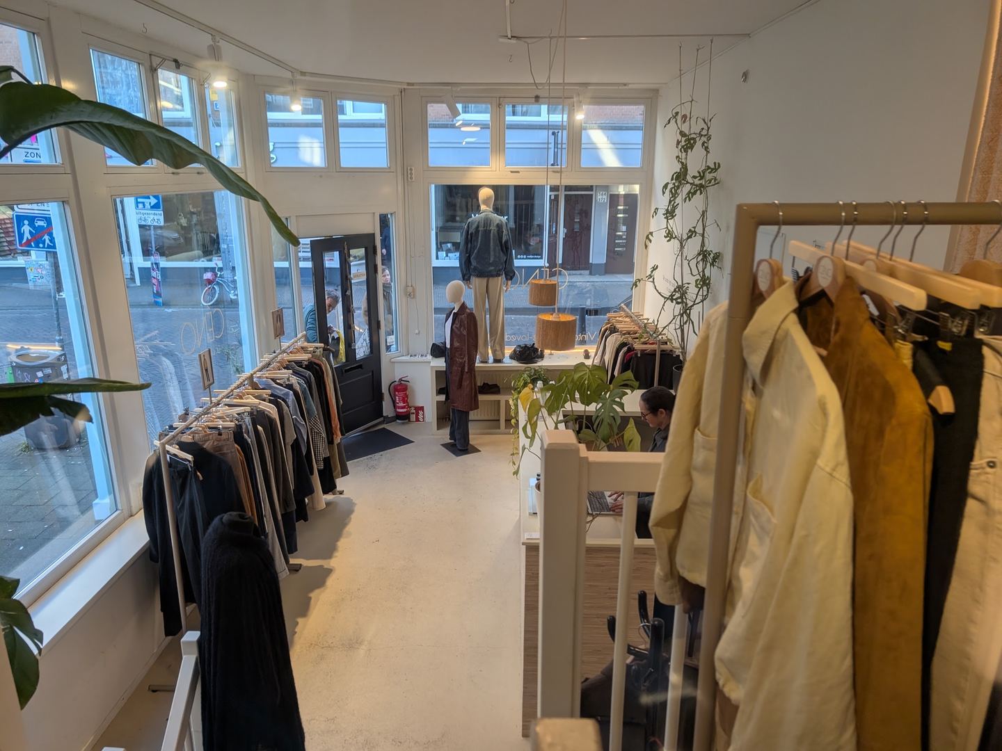 Lichte winkelruimte van CÉNO classics met rekken tweedehands kleding en grote ramen