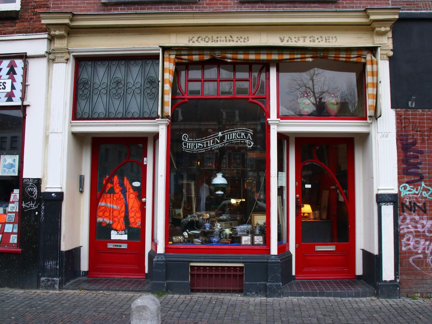 Winkelpui van Christien Jurcka Antiek met rode deuren en een etalage vol antiek en kleingoed