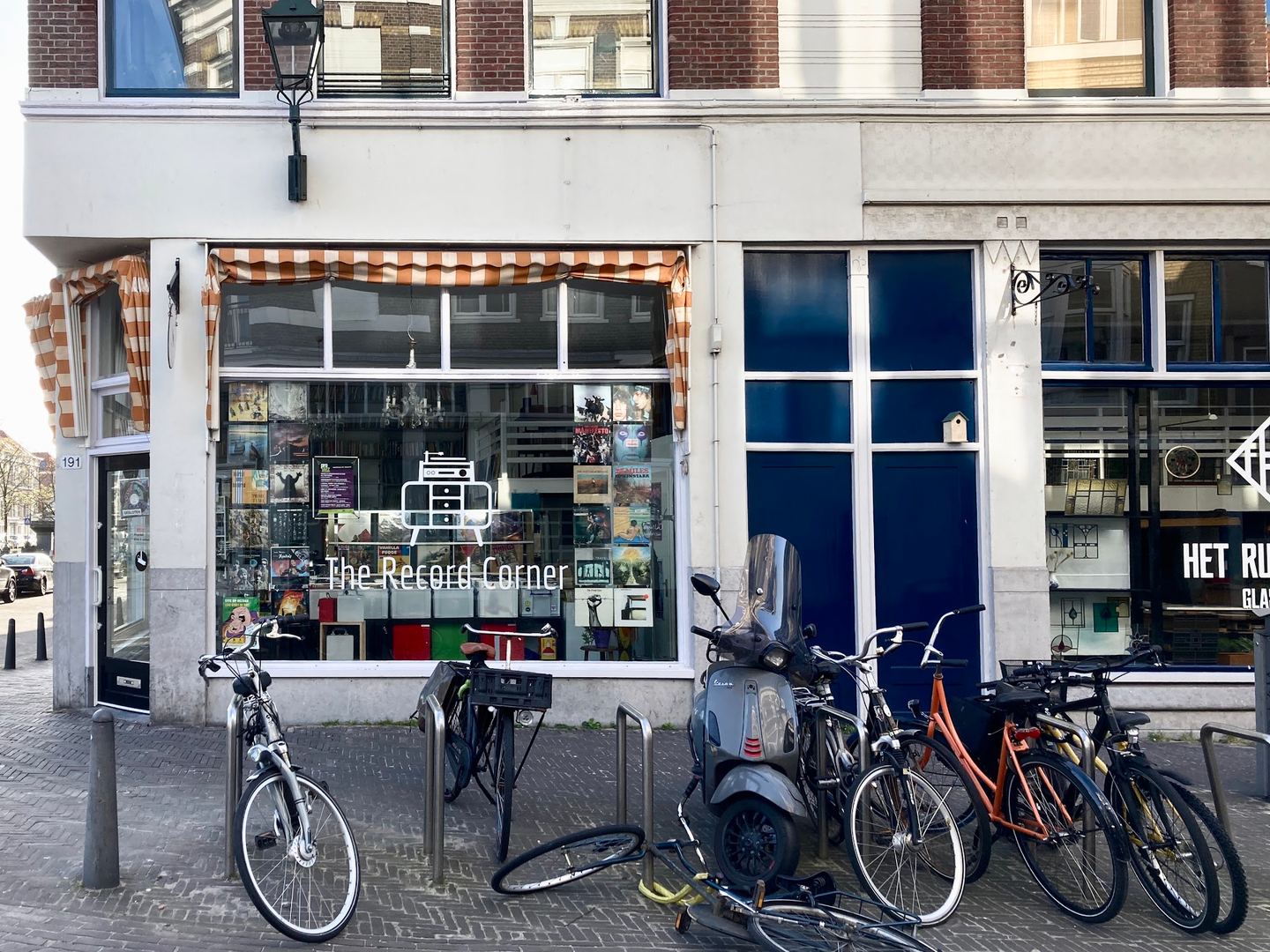 Hoekpand met de winkel van Crazy Horse Recordstore, een gestreepte luifel boven de etalage en fietsen op de stoep