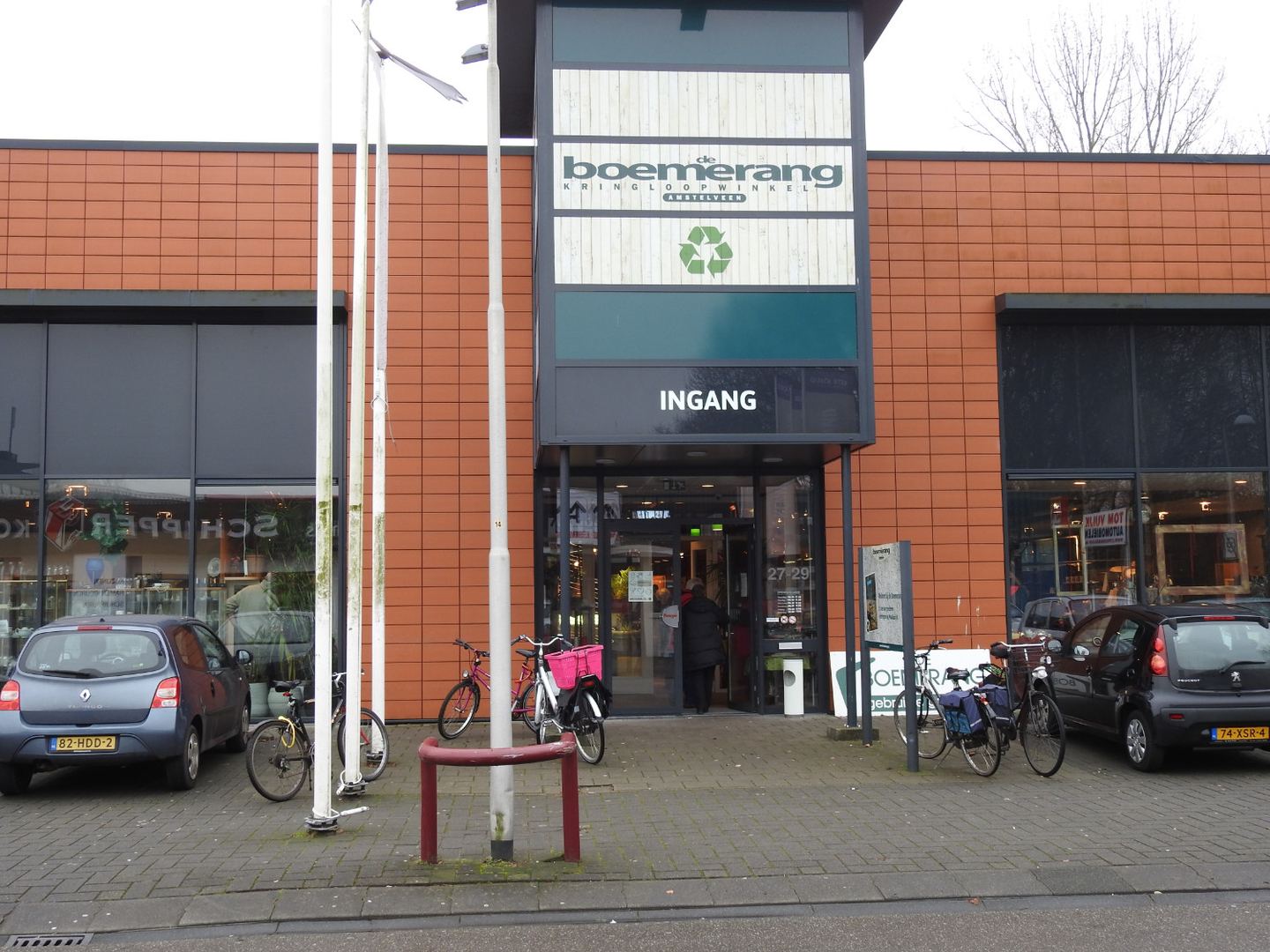 Ingang van De Boem Kringloopwinkel Binderij met het Boemerang-bord en fietsen voor de deur