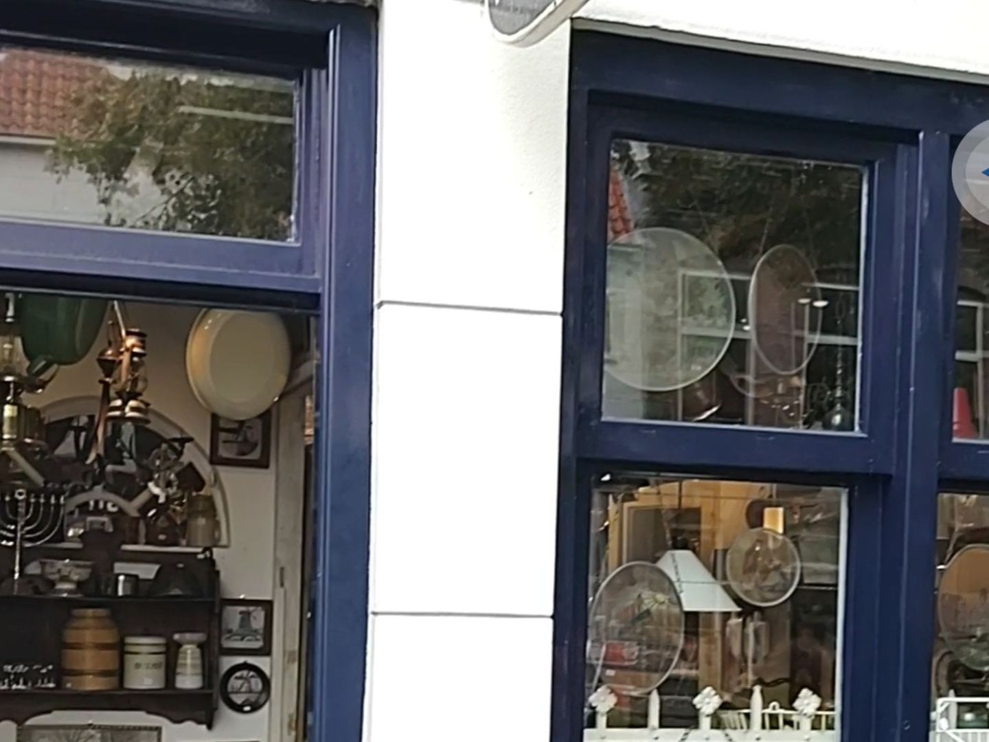 Gevel van De Emaillen Emmer met antiekbord, open deur en emaillewaren voor de etalage