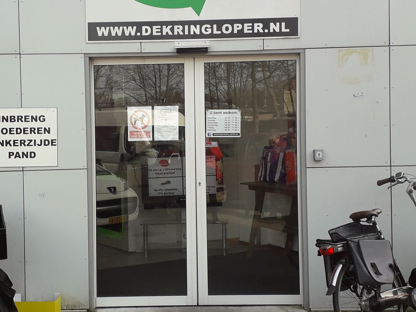 Ingang van De Kringloper Hilversum met het logo boven de glazen deuren