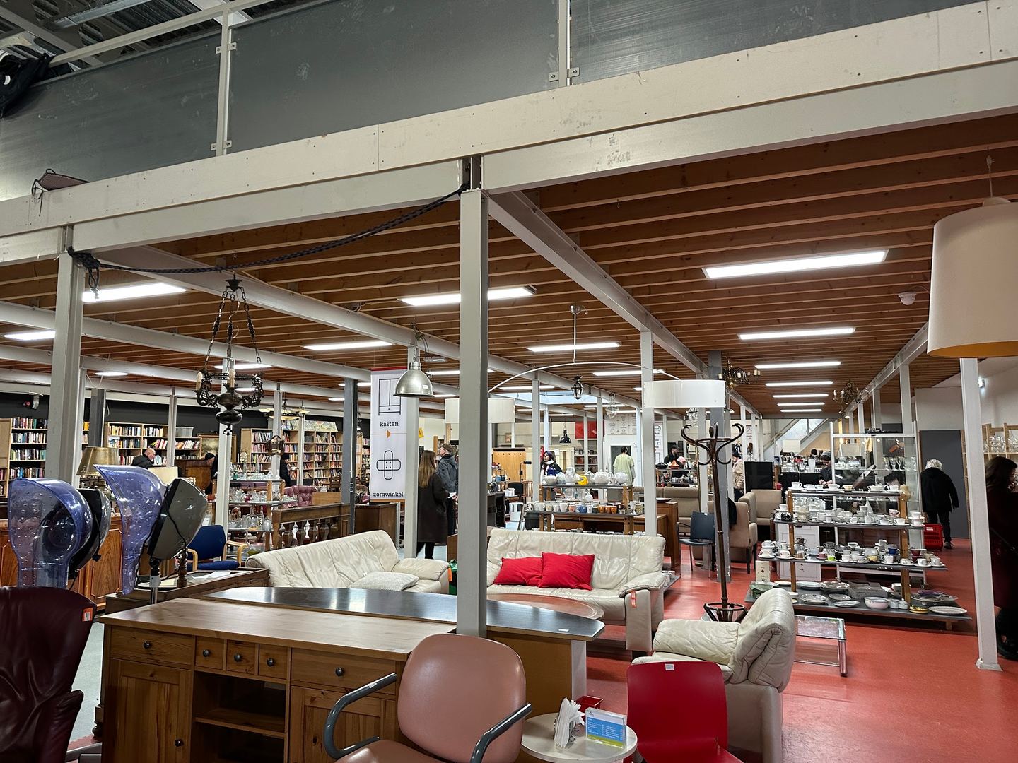 Grote winkelhal van De Lokatie met meubels, lampen en boekenkasten