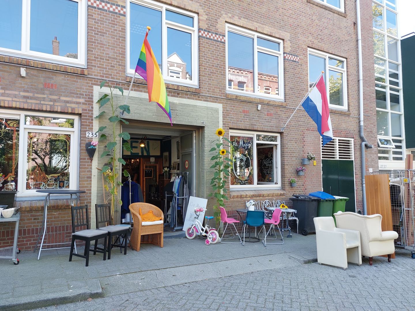 Gevel van De Majum met open deur, vlaggen en stoelen op de stoep